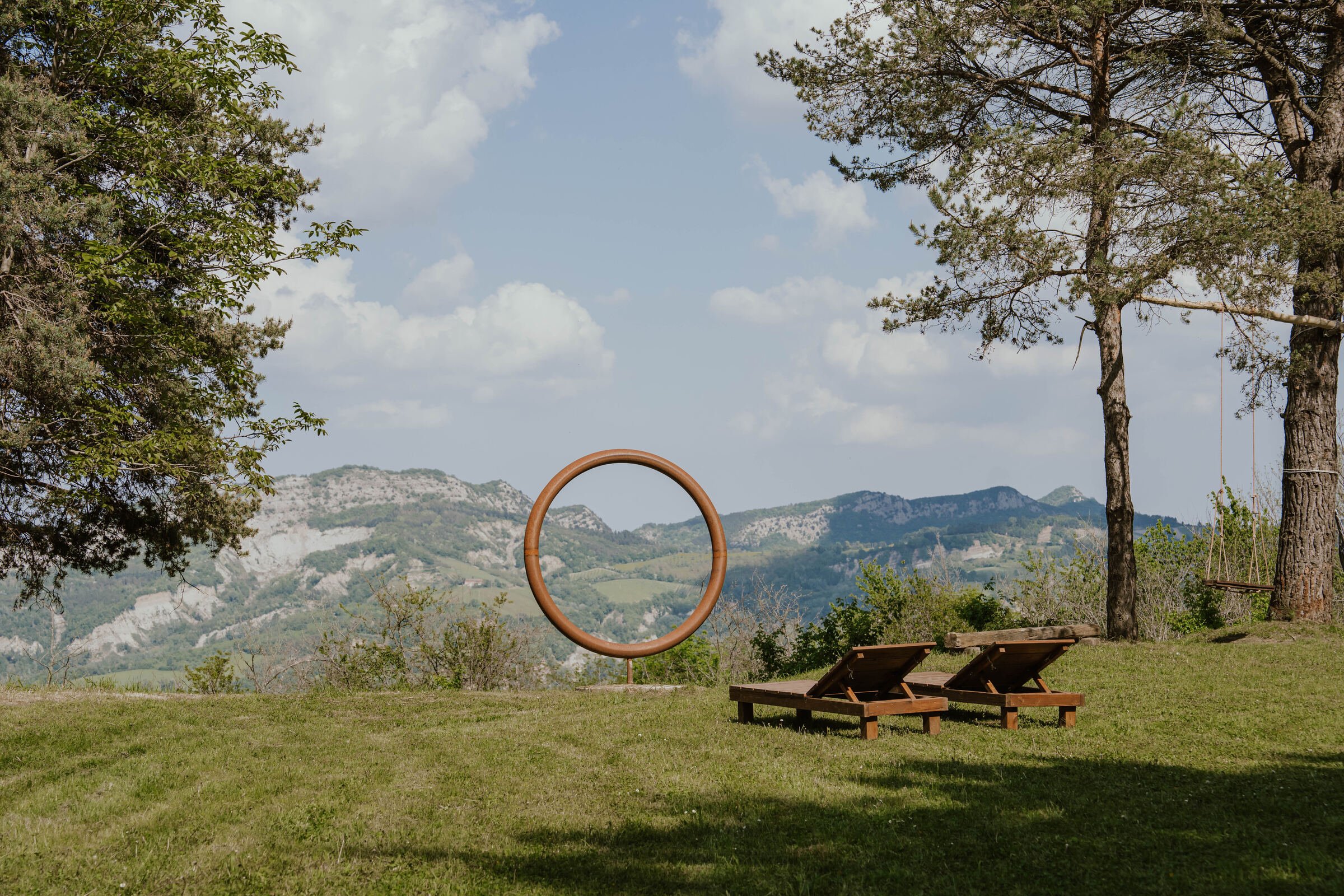 Two sunbeds and the metal ring on the lawn, with the Apennine ridges behind