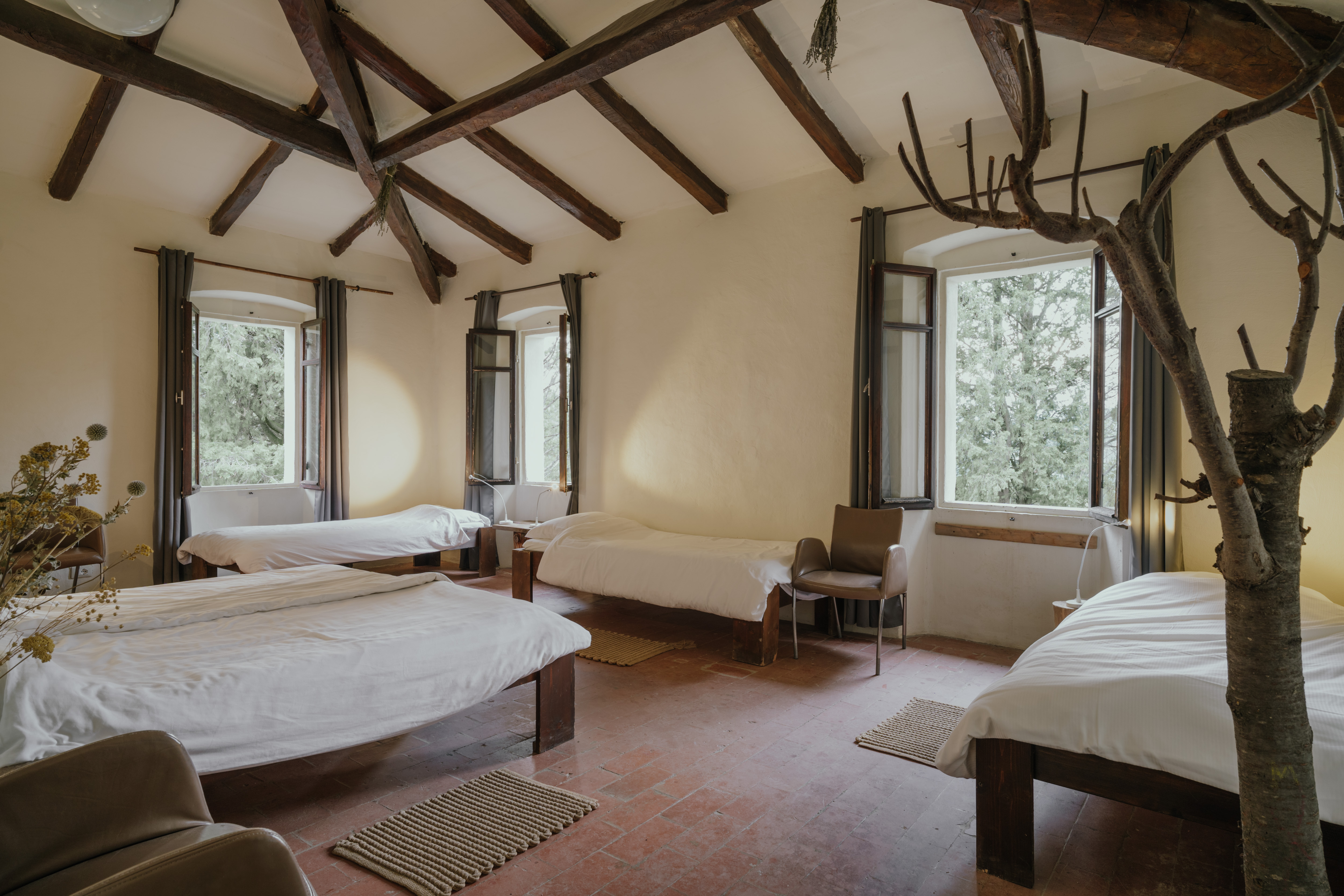 A bedroom with original beamed ceiling, terracotta floors and forest views