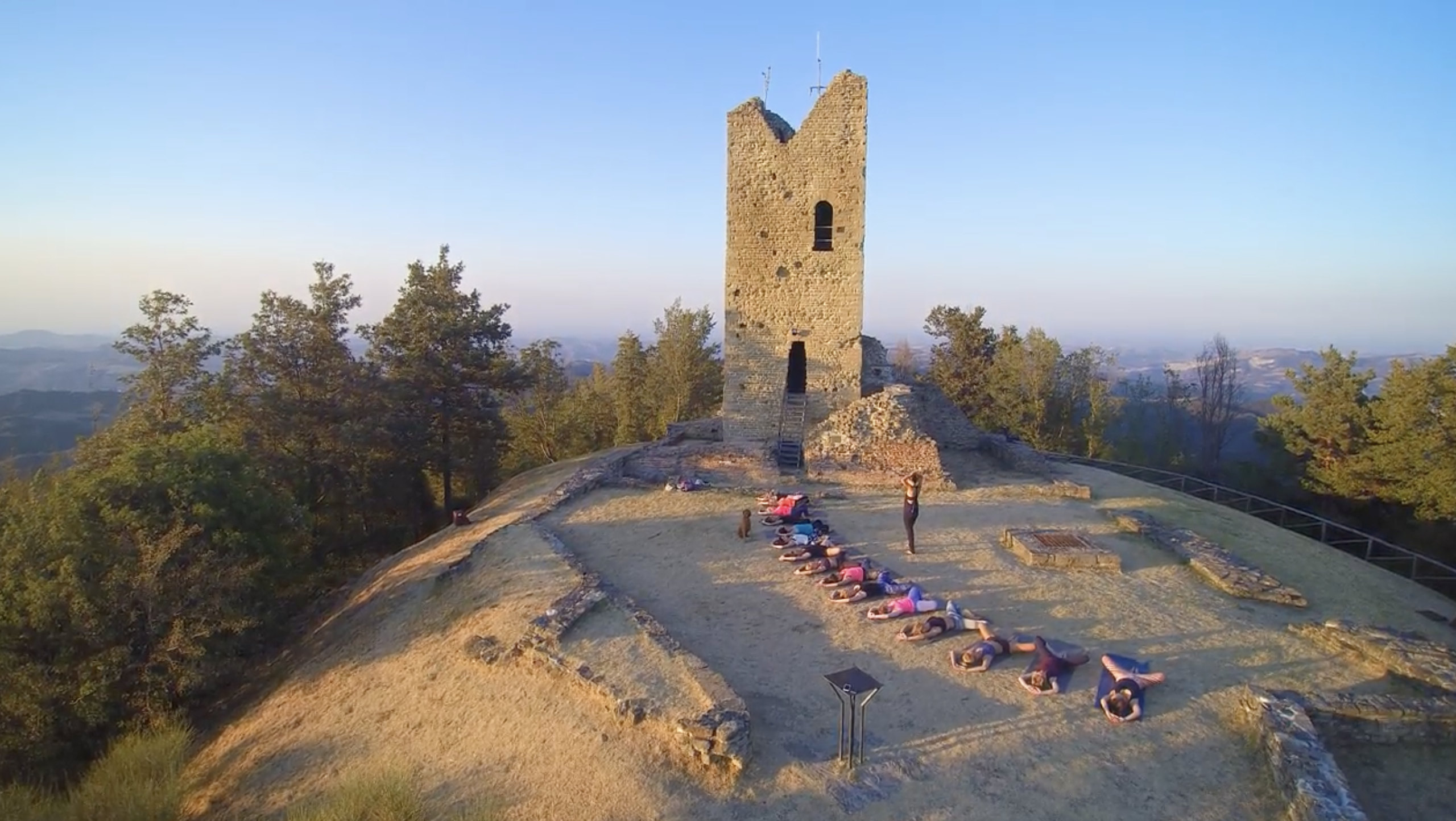Yoga group in savasana at the summit of Monte Battaglia at golden hour