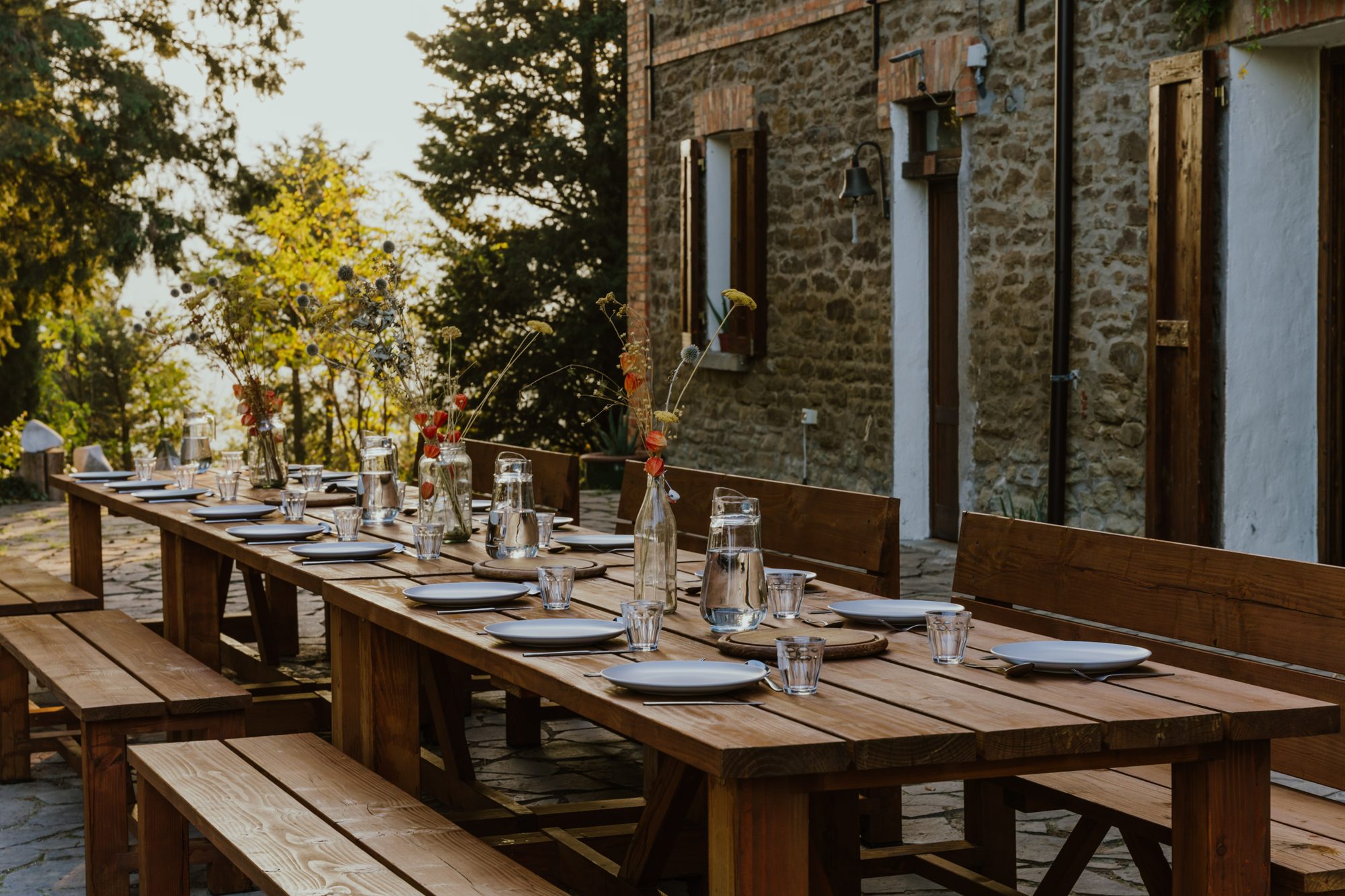 The long terrace table set for dinner beside the stone farmhouse