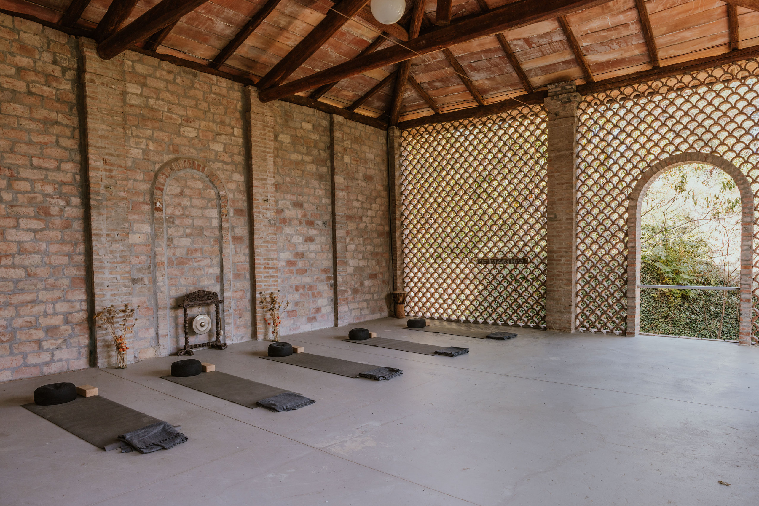 The studio interior with yoga mats, frangisole wall and garden opening